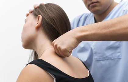 A person wearing a black top receives a chiropractic adjustment on the neck from a practitioner in a light blue uniform. The practitioner's hands are positioned to apply pressure.